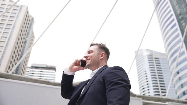 Smart caucasian businessman calling his colleague to plan financial strategy while standing at urban city. Project manager using his mobile phone to communicate with marketing team. Lifestyle. Urbane.