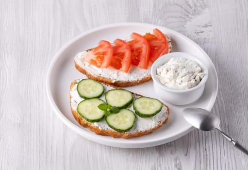 Healthy sandwiches with white cottage cheese, cucumber and tomato.