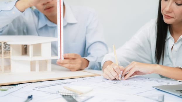 Professional engineer measures house model while skilled designer writes down in blueprint. Work together, collaboration, cooperate. Creative design and team working concept. Closeup. Immaculate