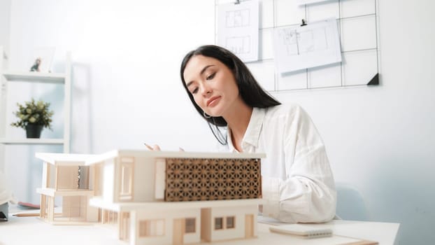 Closeup portrait image of professional young beautiful engineer architect using triangular scale measures house model with focusing at modern office. Business creative design concept. Immaculate.