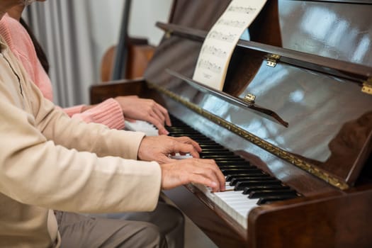 Family. Young woman teaching piano for senior man teaching, happy daughter and elderly father with eyeglasses relaxation playing piano together in living room at home, lifestyle life after retirement