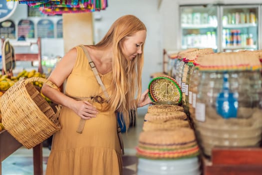 In a grocery store, a pregnant woman stands by a fruit stand, surrounded by various natural foods. She is in a public space where the local market offers whole foods for trade Pregnant woman buying organic vegetables and fruits at Mexican style farmers market