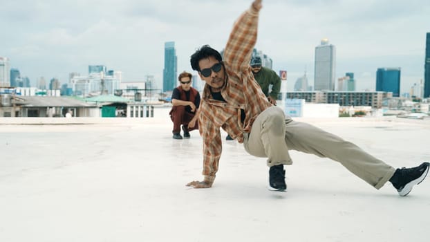 Professional hispanic break dancer practice B boy dance while multicultural friends at roof top. Young modern dancing group doing hip hop movement. Style,fashion,action. Outdoor sport 2024. Endeavor.