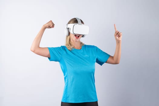 Girl pointing or spinning basketball while using VR glasses. Caucasian woman flexing while wearing casual shirt and visual reality goggles and standing at pink background. Innovation. Contraption.