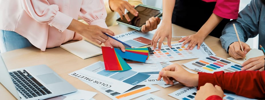 A cropped image of professional interior designer discuss the color material with her colleagues by comparing with color swatches and color palette document. Creative design concept. Variegated.