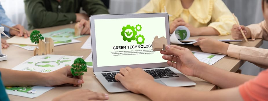 Green technology logo displayed on green business laptop while business team presenting green design to customer. ESG environment social governance and Eco conservative concept. Closeup. Delineation