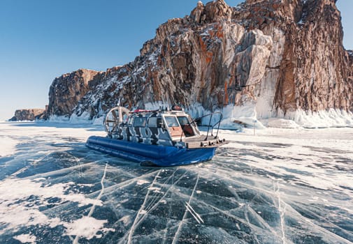 Hovercraft parked on a blue cracked ice of the lake Baikal. Tourists transportation and entertainment on winter Baikal.