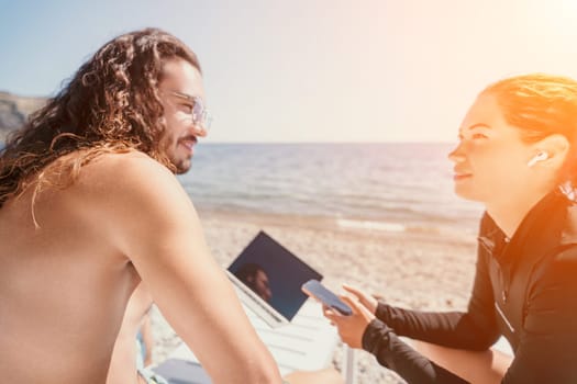 Digital nomad, Business man working on laptop by the sea. Man typing on computer by the sea at sunset, makes a business transaction online from a distance. Freelance, remote work on vacation