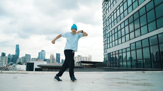 Stylish caucasian dancing man performing break dance at skyscraper. Portrait image of young happy man practicing street dance performance choreographer in modern urban city. Paris style. Endeavor.