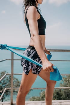 Middle aged well looking woman with black hair doing Pilates with the ring on the yoga mat near the sea on the pebble beach. Female fitness yoga concept. Healthy lifestyle, harmony and meditation.