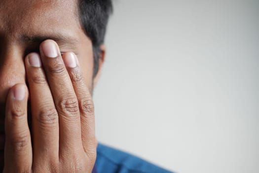 Close up of upset man suffering from strong eye pain.