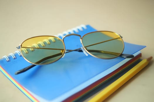 notepad, eyeglass and a pencil on wooden table .