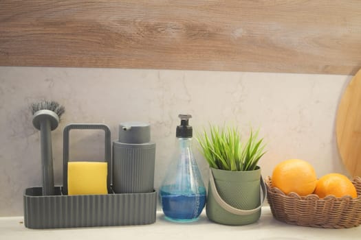 Kitchen counter with cleaning supplies and a basket of oranges,