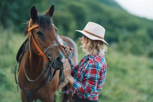 Happy blonde with horse in forest. Woman and a horse walking through the field during the day. Dressed in a plaid shirt and black leggings