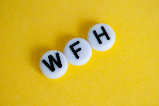 Top view of WFH text representing work from home on yellow background.