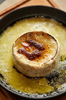 Close-up of Camembert wheel melted until bubbly and browned top in black iron skillet, perfect for decadent cheese dip sauce