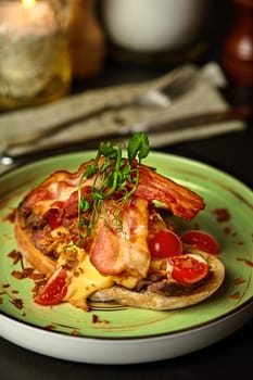 Appetizing Italian bruschetta with slices of veal steak, piquant sauce, crispy onions and fried bacon garnished with fresh greens and cherry tomatoes served on ceramic plate