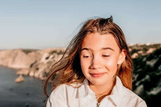 Brown-haired young romantic teenager girl corrects long hair on beach at summer evening wind