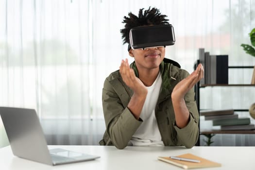 Surprised young African American looking through VR holding interesting data object hologram metaverse world connecting digital futuristic technology virtual reality meta modern office. Contrivance.