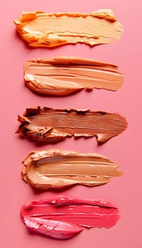 A row of different shades of lipstick on a pink background resembles a palette of vibrant colors. The magenta and peach hues evoke thoughts of sweetness and baked goods