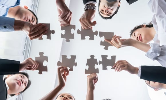 Multiethnic business people holding jigsaw pieces and merge them together as effective solution solving teamwork, shared vision and common goal combining diverse talent. Below view. Habiliment