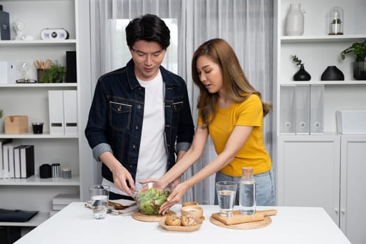 Cooking show on live streaming with two chef influencers teaching mixed salad with dressing for easy special menu at home. Ingredients placing on table with bread bun wholegrain side dish. Infobahn.