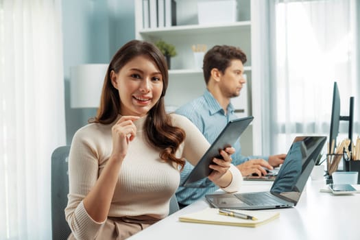 Smiling beautiful woman holding tablet to recheck list, looking at camera photo shooting portrait business pose profile while working with smart coworker at modern office at morning time. Postulate.