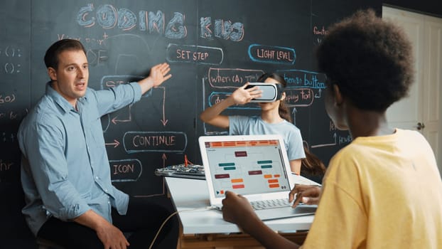 Girl wear VR glass while mentor pointing at blackboard and explain engineering code. African student writing system while receive advice from teacher at table with electronic equipment. Edification.