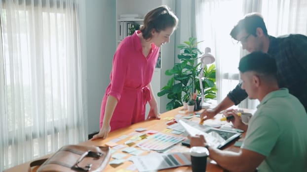 Skilled caucasian business woman present theme color to diverse investor. Multicultural people planning and making decision for choosing color for product while sitting at meeting table. Symposium.