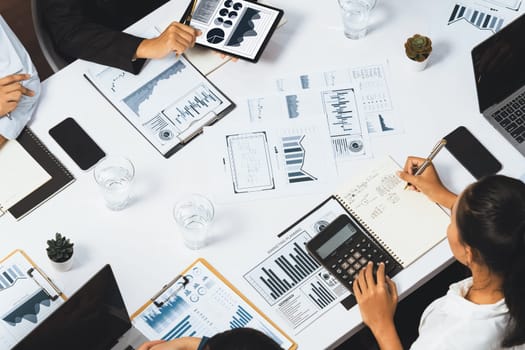 Top view analyst team utilizing BI Fintech to analyze financial data at table in meeting room. Analytic BI dashboard power on paper for business insight and strategic marketing planning. Prudent