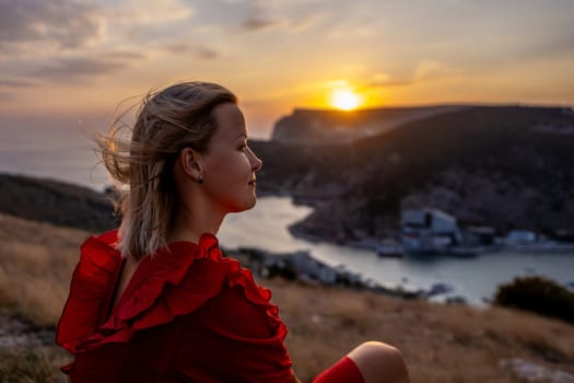 Woman sunset sea mountains. Happy woman siting with her back on the sunset in nature in summer posing with mountains on sunset, silhouette. Woman in the mountains red dress, eco friendly, summer landscape active rest.