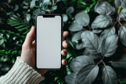 A man is standing in front of a plant while holding an phone in his hand, showcasing modern technology and nature. Mockup