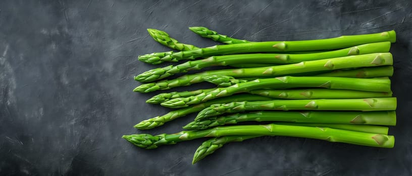 A bunch of green asparagus displayed on a black surface.