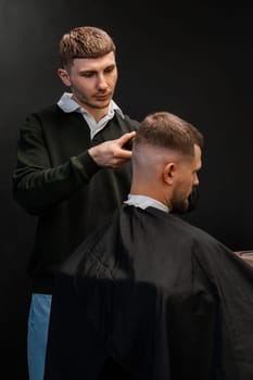 Skilled barber cuts client short hair with electrical trimmer in barbershop closeup. Hairdresser does stylish men haircut in beauty shop