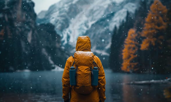 Lone trekker facing snowy peaks at dusk.