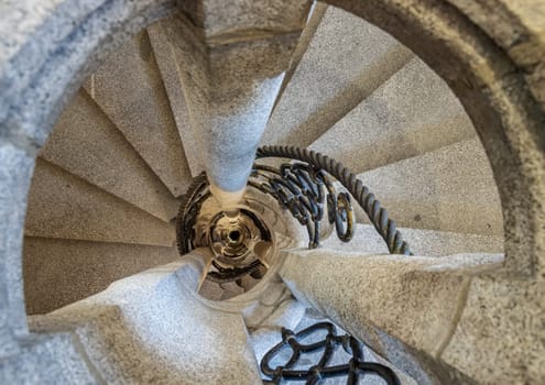 Munich, Germany - Dec 21, 2023 - Upside view of The old stone spiral staircase with iron railing inside columnar structures. Ladder decoration interior of building, Copy space, Selective focus.