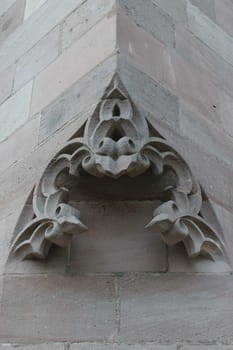Close-up of a decorative stone carving on the corner of a building, featuring intricate floral patterns.