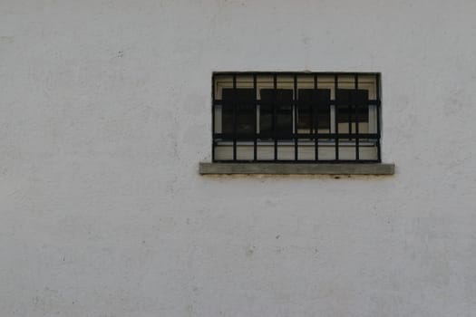 A small barred window on a plain white wall.