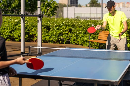 Family playing table tennis outside house. High quality photo