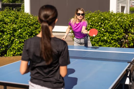 Adult woman instructor teaching girl play table tennis. High quality photo