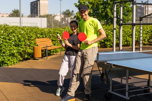 Happy man with his daughter playing ping pong in park. High quality photo