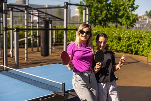 mother and daughter play ping pong in park. High quality photo