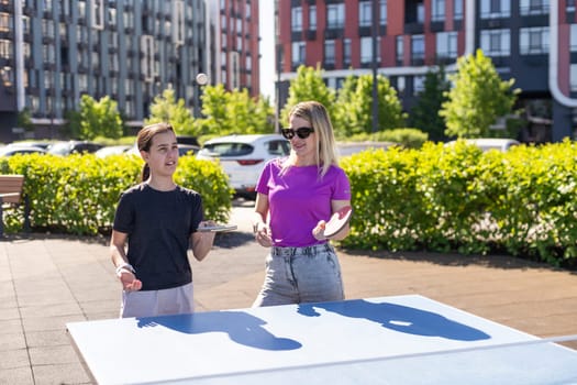 mother and daughter play ping pong in park. High quality photo