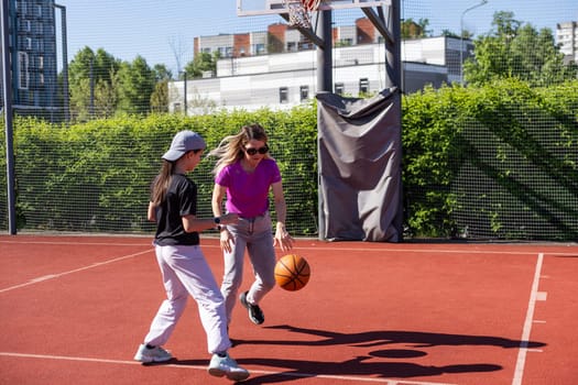 Concept of sports, hobbies and healthy lifestyle. Young people playing basketball on playground outdoors. High quality photo