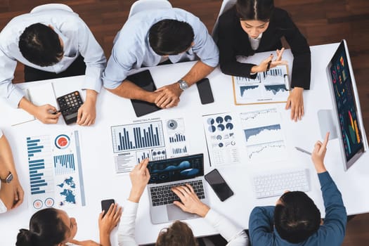 Top view analyst team utilizing BI Fintech to analyze financial data at table in meeting room. Analytic BI dashboard power on paper for business insight and strategic marketing planning. Prudent