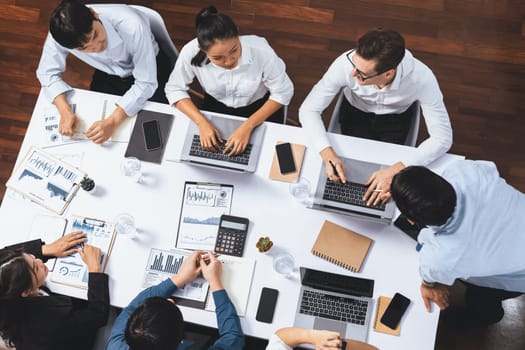 Top view analyst team utilizing BI Fintech to analyze financial data at table in meeting room. Analytic BI dashboard power on paper for business insight and strategic marketing planning. Prudent