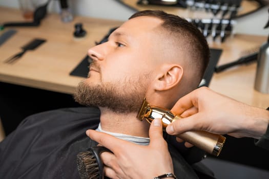 Barber skillfully uses a trimmer to shape the clients beard, focusing on the contours of the cheek.