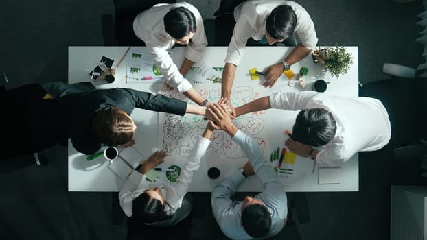 Top down view of business team discussing about using clean energy and sustainable investment at meeting table with wind mill, document with environmental graph and wooden house model. Alimentation.