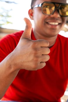 Closeup of a young latin man pointing thumb up. Confident facial expression.