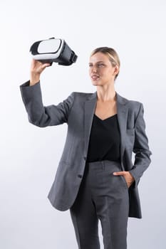 Caucasian business woman holding VR glass while standing at white background. Professional project manager looking visual reality goggle while wearing suit. Innovation technology concept. Contraption.